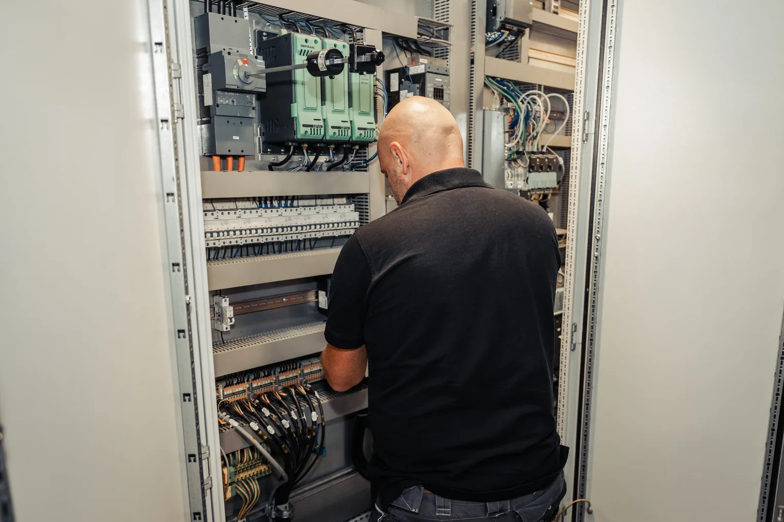 Elektriker verdrahtet einen offenen Industrieschaltschrank