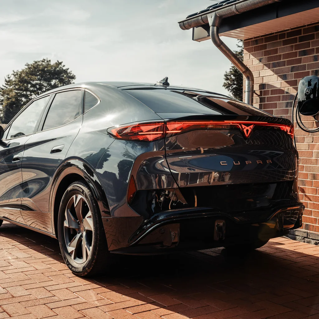 Elektroauto an einer Wallbox vor einem Wohnhaus